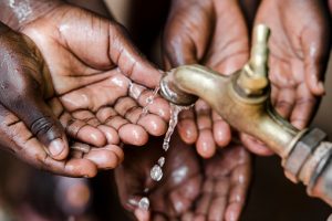 many hands catching water under a faucet