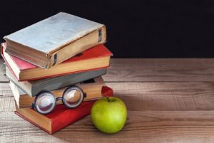 a pair of glasses, an apple, and a stack of books