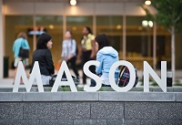 the word "Mason" set up outdoors on campus with people walking behind